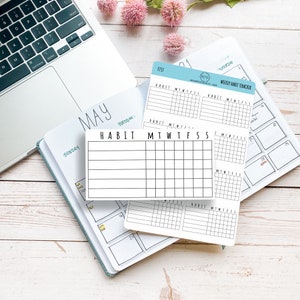 K&ouml;nnte beinhalten: Nahaufnahme eines wei&szlig;en Habit Trackers mit den Worten "HABIT" und "MTWTFSS" darauf gedruckt. Der Tracker liegt auf einem Planer mit dem Monat Mai und den Wochentagen darauf gedruckt.