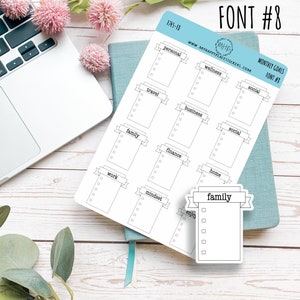 May include: A sheet of printable stickers with a banner design. The stickers are for monthly goals and include categories such as personal, wellness, travel, business, family, finance, work, mindset, and home. The stickers are black and white and have a simple design.