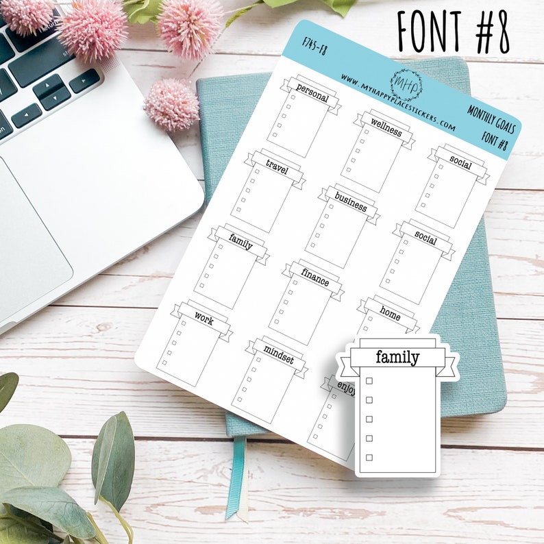 May include: A sheet of printable stickers with a banner design. The stickers are for monthly goals and include categories such as personal, wellness, travel, business, family, finance, work, mindset, and home. The stickers are black and white and have a simple design.