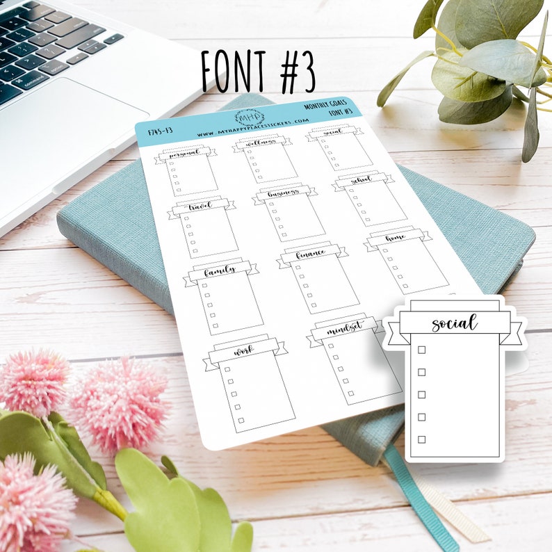 May include: A printable sheet of monthly goal stickers with a banner design. The stickers are labelled with categories such as personal, wellness, travel, business, school, family, finance, home, work, mindset, and social.