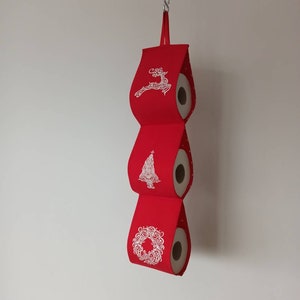 Porta carta igienica in tessuto ricamato: tessuto rosso con decorazioni natalizie bianche. Cervo, albero di Natale, angelo.