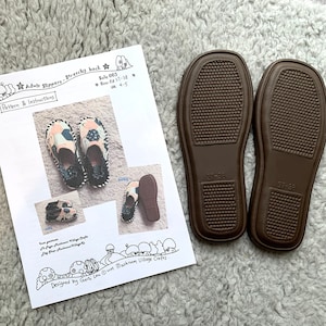 Pode incluir: Um close-up de um par de solas de borracha marrom para pantufas para adultos. As solas têm um padrão texturizado e o texto "37-38" é impresso na parte inferior de cada sola. As solas são mostradas ao lado de uma folha de papel com instruções para fazer pantufas para adultos. O papel tem um logotipo do Mushroom Village Crafts e o texto "Sale 003", "37-38" e "UK 4-5" impresso nele.