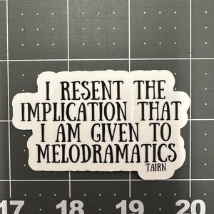 Puede incluir: Una pegatina blanca con texto negro. El texto dice: "I RESENT THE IMPLICATION THAT I AM GIVEN TO MELODRAMATICS". La pegatina tiene una forma irregular y la palabra "TAIRN" est&aacute; impresa en la parte inferior.