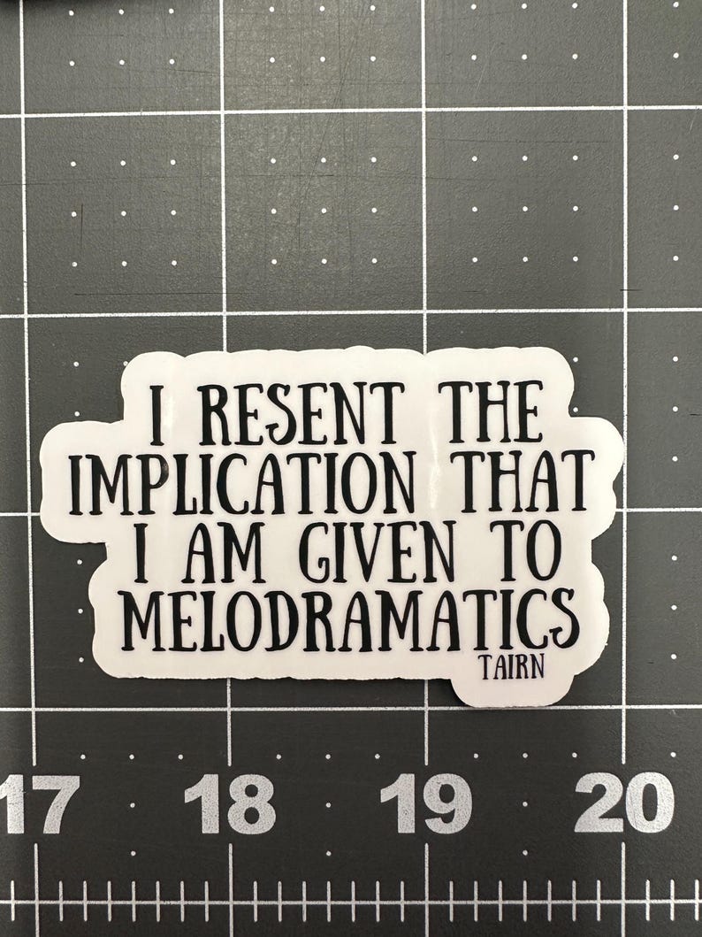 Puede incluir: Una pegatina blanca con texto negro. El texto dice: "I RESENT THE IMPLICATION THAT I AM GIVEN TO MELODRAMATICS". La pegatina tiene una forma irregular y la palabra "TAIRN" est&aacute; impresa en la parte inferior.