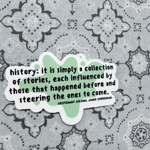 Peut inclure: Un autocollant vert avec un motif de papillon et la citation "history: it is simply a collection of stories, each influenced by those that happened before and steering the ones to come." La citation est attribu&eacute;e au lieutenant-colonel Asher Sorrengail.