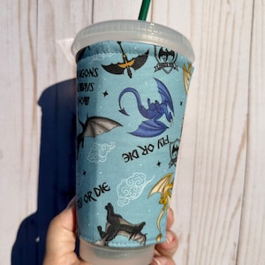 May include: A blue reusable cup sleeve with a dragon design. The sleeve features multiple dragons in various poses, including flying, perched, and in mid-air. The text "Fly or Die" is repeated on the sleeve.