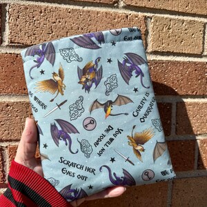 May include: A blue fabric pouch with a repeating pattern of dragons, keys, and clouds. The pouch has the text "We Eat Our" at the top, "Scratch Her Eyes Out" at the bottom, and "Die Today You Will Fill Not" in the middle. The text "Civility Is Overrated" is on the right side of the pouch.