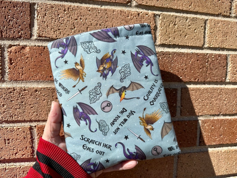 May include: A blue fabric pouch with a repeating pattern of dragons, keys, and clouds. The pouch has the text "We Eat Our" at the top, "Scratch Her Eyes Out" at the bottom, and "Die Today You Will Fill Not" in the middle. The text "Civility Is Overrated" is on the right side of the pouch.