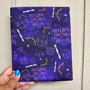 May include: Purple fabric with a repeating pattern of bats, swords, bows and arrows, and the text "Only you can decide what breaks you".