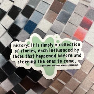Peut inclure: Un autocollant vert avec un motif de papillon et le texte "history: it is simply a collection of stories, each influenced by those that happened before and steering the ones to come." Le texte est attribu&eacute; &agrave; "LIEUTENANT COLONEL ASHER SORRENGAIL".