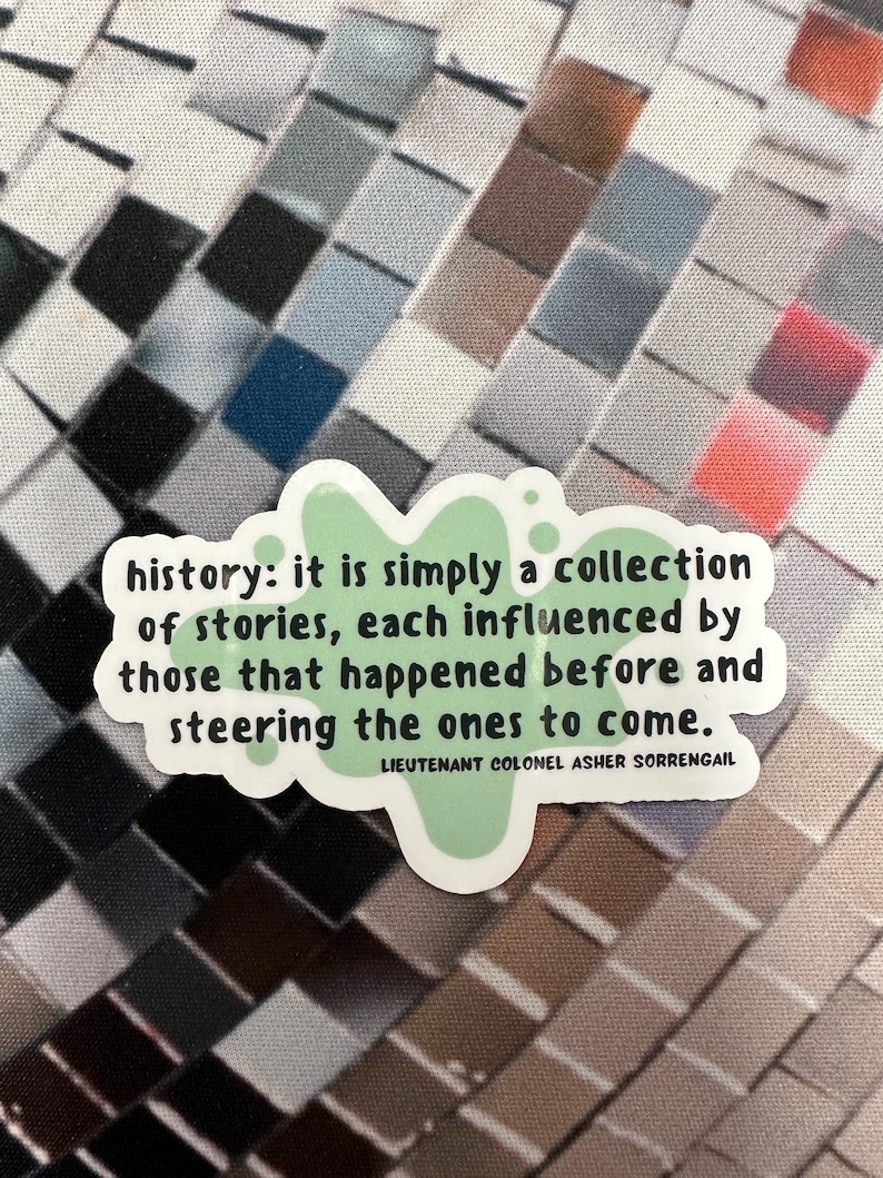 Peut inclure: Un autocollant vert avec un motif de papillon et le texte "history: it is simply a collection of stories, each influenced by those that happened before and steering the ones to come." Le texte est attribu&eacute; &agrave; "LIEUTENANT COLONEL ASHER SORRENGAIL".