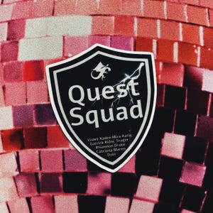 May include: Black and white shield sticker with the text "Quest Squad" and a lightning bolt. The sticker has a small dragon graphic and a list of names: Violet, Xaden, Mira, Aaric, Garrick, Ridoc, Trager, Rhiannon, Drake, Catriona, Maren, Dain.