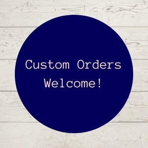 May include: A dark blue circle with white text that says "Custom Orders Welcome!" on a white wood background.