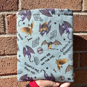 May include: A blue fabric pouch with a repeating pattern of dragons, griffins, and swords. The text "We Do Eat Our" and "Civility is Overrated" is printed on the pouch.