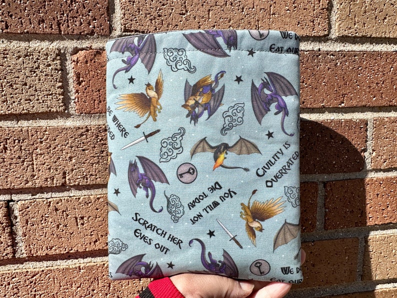 May include: A blue fabric pouch with a repeating pattern of dragons, griffins, and swords. The text "We Do Eat Our" and "Civility is Overrated" is printed on the pouch.