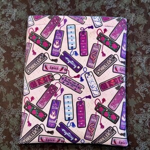 May include: A pink fabric pouch with a repeating pattern of purple and white bookmarks with various text, including "Thriller", "Mystery", "Spice", "Slow Burn", "Book Worm", and "One More Chapter".