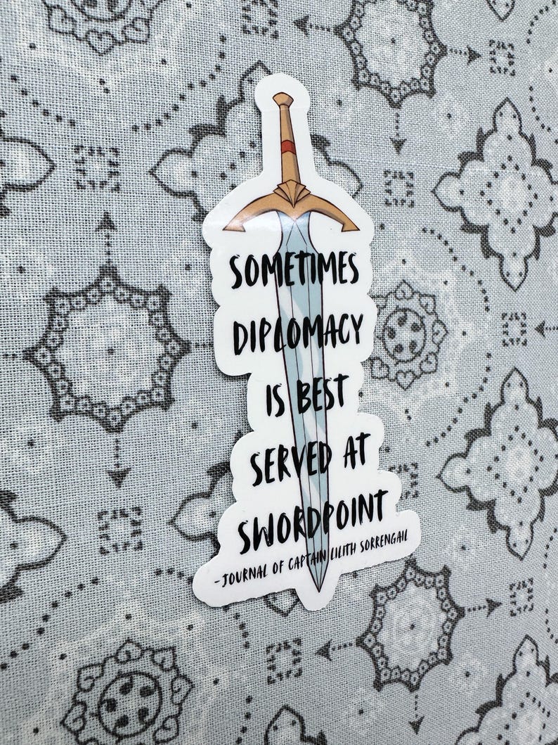 Puede incluir: Una pegatina blanca con una espada azul y el texto "Sometimes diplomacy is best served at swordpoint - Journal of Captain Lilith Sorrengail"