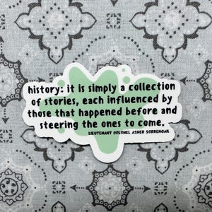 Peut inclure: Un autocollant vert et blanc avec une citation sur l'histoire&nbsp;: &laquo;&nbsp;history&nbsp;: it is simply a collection of stories, each influenced by those that happened before and steering the ones to come.&nbsp;&raquo; La citation est attribu&eacute;e au lieutenant-colonel Asher Sorrengail.