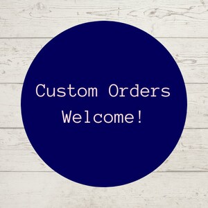 Pu&ograve; includere: Un cerchio blu scuro con testo bianco che dice "Ordini personalizzati Benvenuti!" su uno sfondo di legno bianco.