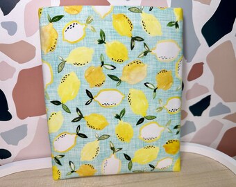May include: A light blue fabric pouch with a lemon print. The lemons are yellow with white centers and green leaves. The fabric has a subtle texture.