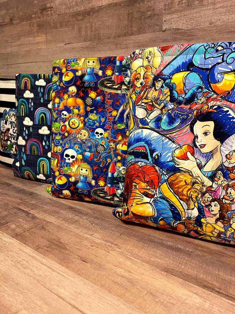 Pu&ograve; includere: Quattro borse tote colorate con vari disegni di personaggi Disney. Le borse sono realizzate in tessuto e hanno una texture trapuntata. I disegni includono personaggi di Toy Story, Il Re Leone, Aladdin e Biancaneve.