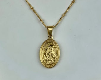 May include: A gold chain necklace with a gold oval pendant featuring a religious image. The pendant has the words "Santa Maria" and "Ora Pro Nobis" inscribed on it.