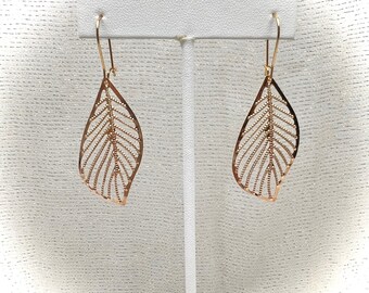 May include: A pair of gold leaf-shaped earrings hanging from a white display stand.