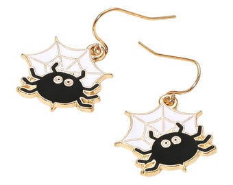May include: A pair of gold-tone metal dangle earrings. Each earring features a black spider with white web detail. The spider has two large eyes and is outlined in gold. The earrings are designed for pierced ears.