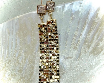 May include: Gold dangle earrings with a square clear crystal at the top and a chain of small gold circles with clear crystals throughout.