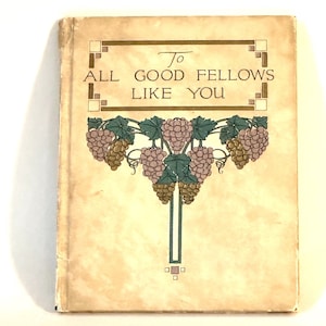 May include: A vintage book with a cream-colored cover and a decorative design featuring a vine with purple grapes and green leaves. The title on the cover reads "To All Good Fellows Like You".