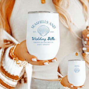 May include: White insulated wine tumbler with the text "SEASHELLS AND Wedding Bells" and a seashell graphic in blue. The tumbler includes the text "SARAH'S BACHELORETTE SAINT VINCENT". A smaller version of the tumbler is also visible.