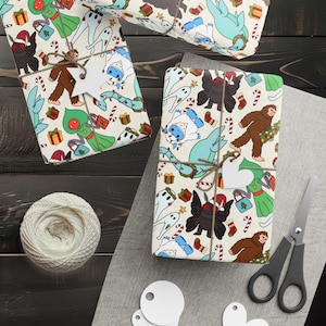 May include: Several wrapped gifts with a festive pattern featuring cartoon monsters, candy canes, and presents. The gifts are tied with twine and have blank white tags. A ball of twine, scissors, and additional tags are also visible.