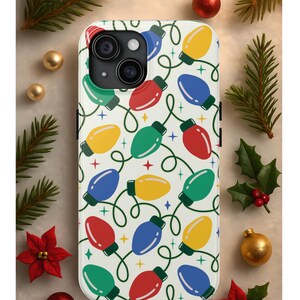 May include: A white phone case featuring a repeating pattern of colorful Christmas lights in red, green, blue, and yellow. The lights are connected by a green wire and set against a background of small stars. The case is surrounded by Christmas decorations.
