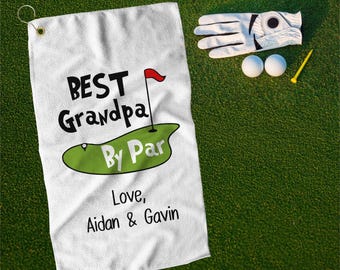 May include: White golf towel with the text "BEST Grandpa By Par" and a green golf course with a red flag. Below the text is "Love, Aidan & Gavin".