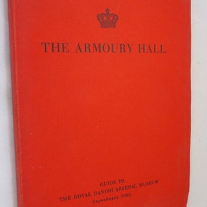 May include: Red book cover with a gold crown and the text "THE ARMOURY HALL" in black. The text "GUIDE TO THE ROYAL DANISH ARSENAL MUSEUM Copenhagen 1953." is printed in black at the bottom.