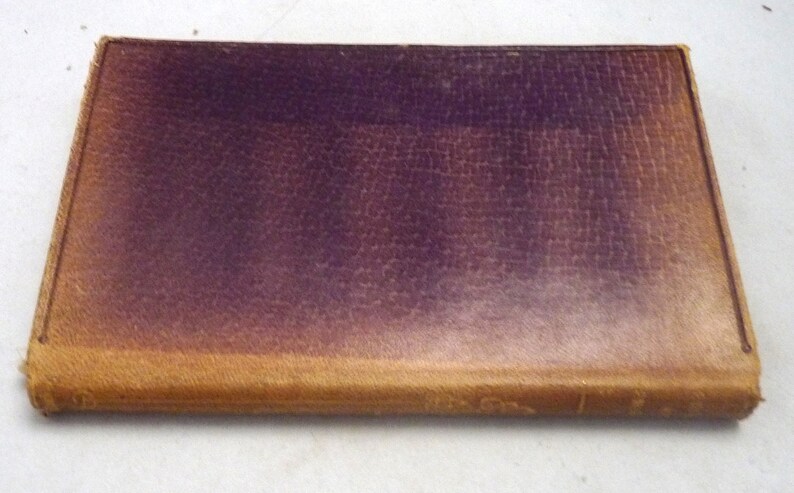 May include: A vintage leather-bound book with a dark purple cover and a light brown spine.