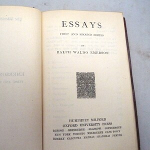 May include: A book titled "Essays: First and Second Series" by Ralph Waldo Emerson. The book cover is cream colored with black text and a decorative black and white design. The book is published by Humphrey Milford, Oxford University Press.