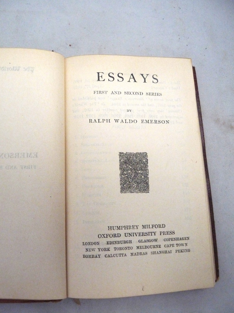 May include: A book titled "Essays: First and Second Series" by Ralph Waldo Emerson. The book cover is cream colored with black text and a decorative black and white design. The book is published by Humphrey Milford, Oxford University Press.