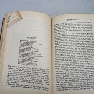 May include: An open book with yellowed pages, showing a poem about friendship. The text is in black ink and the book has a brown leather cover.