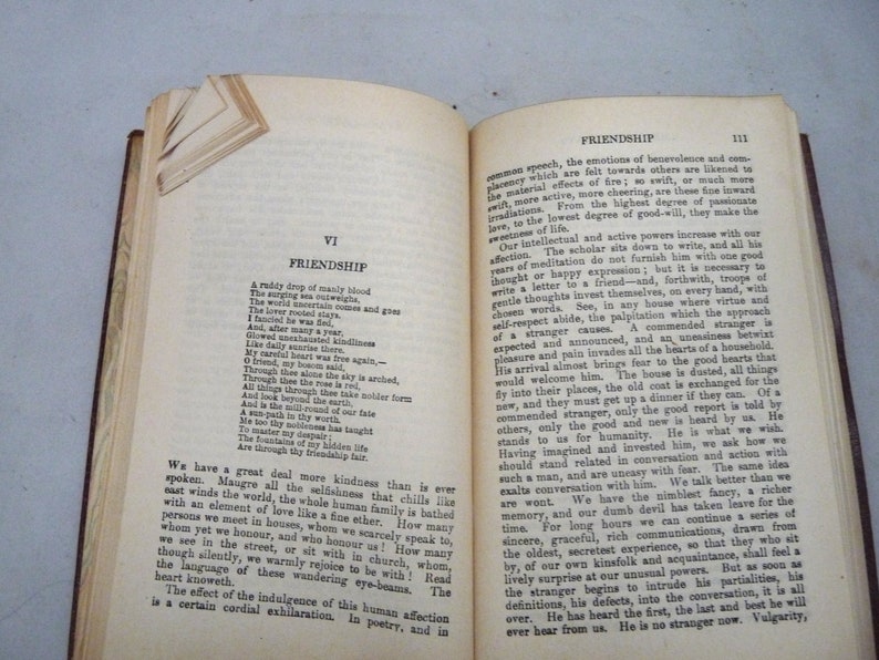 May include: An open book with yellowed pages, showing a poem about friendship. The text is in black ink and the book has a brown leather cover.