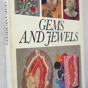 May include: A book titled "Color Treasury of Gems and Jewels" with a white cover and colorful images of gems and jewelry. The book is published by Crescent.