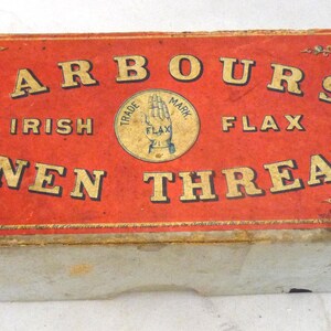 May include: A red and white cardboard box with the text "Barbour's Irish Flax Linen Thread" printed on the front. The box has a decorative border with images of a hand holding flax and other designs.