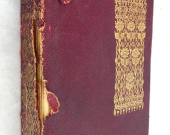 May include: A burgundy hardback book with gold lettering and a decorative design on the cover. The title of the book is "The Man Who Laughs" by Alexandre Dumas.