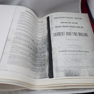 May include: A black and white instruction book for a garment drafting machine. The book is titled "Instruction Book Drafting and Cutting Dresses, Basques, Sacques, Coats, &c. By the Garment Drafting Machine As Invented and Patented by A. McDowell. The McDowell Garment Drafting Machine Company, 6 West 14th Street, New York, U.S.A."