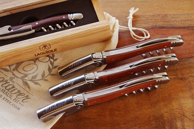 K&ouml;nnte beinhalten: Set aus drei personalisierten Laguiole-Korkenziehern mit Holzgriffen. Die Korkenzieher sind mit den Namen "Tim", "Craig" und "Michael" graviert.