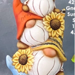 May include: A stack of four gnomes with sunflower hats. The bottom gnome's hat says "Hi Shine". The second gnome's hat is orange and says "Love". The third gnome's hat is yellow and striped. The top gnome's hat is yellow with a sunflower.