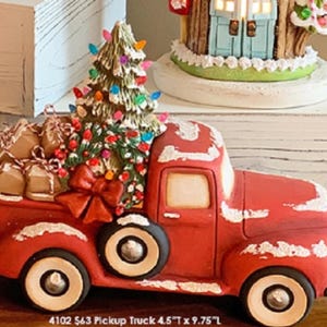 May include: A red vintage pickup truck with white accents, carrying a decorated Christmas tree and wrapped gifts. The truck is 4.5 inches tall and 9.75 inches long.