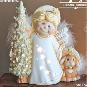 May include: A ceramic angel figurine holding a Christmas tree with lights. The angel has blonde hair, blue eyes, and a white dress with star cutouts. A small dog figurine with a star hat is also present.