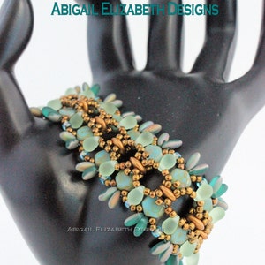 Puede incluir: Pulsera de cuentas con diseño de enrejado de panal, con cuentas de color turquesa y dorado. La pulsera se muestra sobre una forma negra con forma de mano. El texto de la imagen dice "HONEYCOMB LATTICE BRACELET TUTORIAL" y "ABIGAIL ELIZABETH DESIGNS".