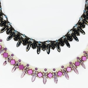 May include: Two beaded necklaces. One is black with teardrop-shaped beads and blue accents. The other is white with purple square and leaf-shaped beads. Both have intricate designs and are set against a white background.